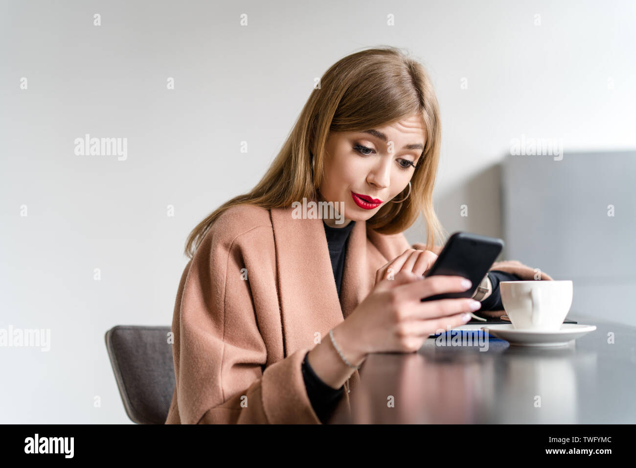 Überrascht Frau trinkt Kaffee und Ihr Mobiltelefon Stockfoto