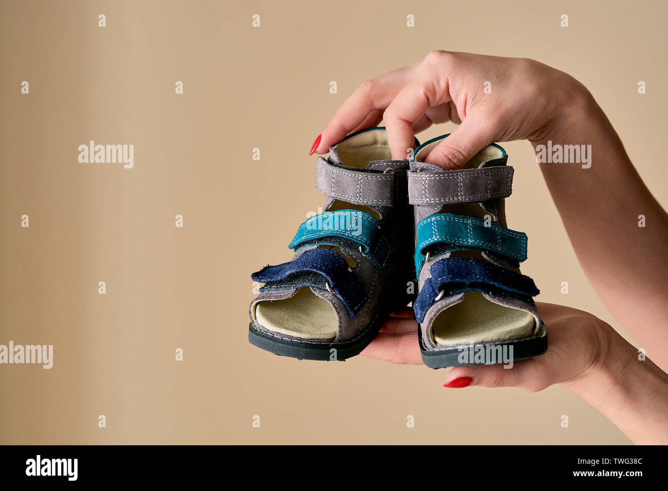 Weibliche hält Close-up ist ein spezielles Kinder orthopädische Schuhe Sandalen aus echtem Leder. Bequeme Schuhe auf hellen Hintergrund isoliert mit c Stockfoto