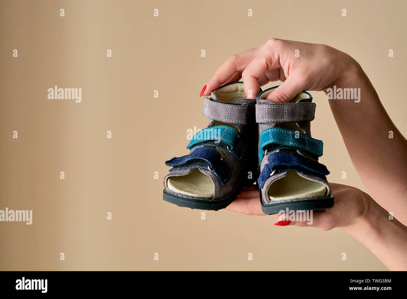 Weibliche hält Close-up ist ein spezielles Kinder orthopädische Schuhe Sandalen aus echtem Leder. Bequeme Schuhe auf hellen Hintergrund isoliert mit c Stockfoto