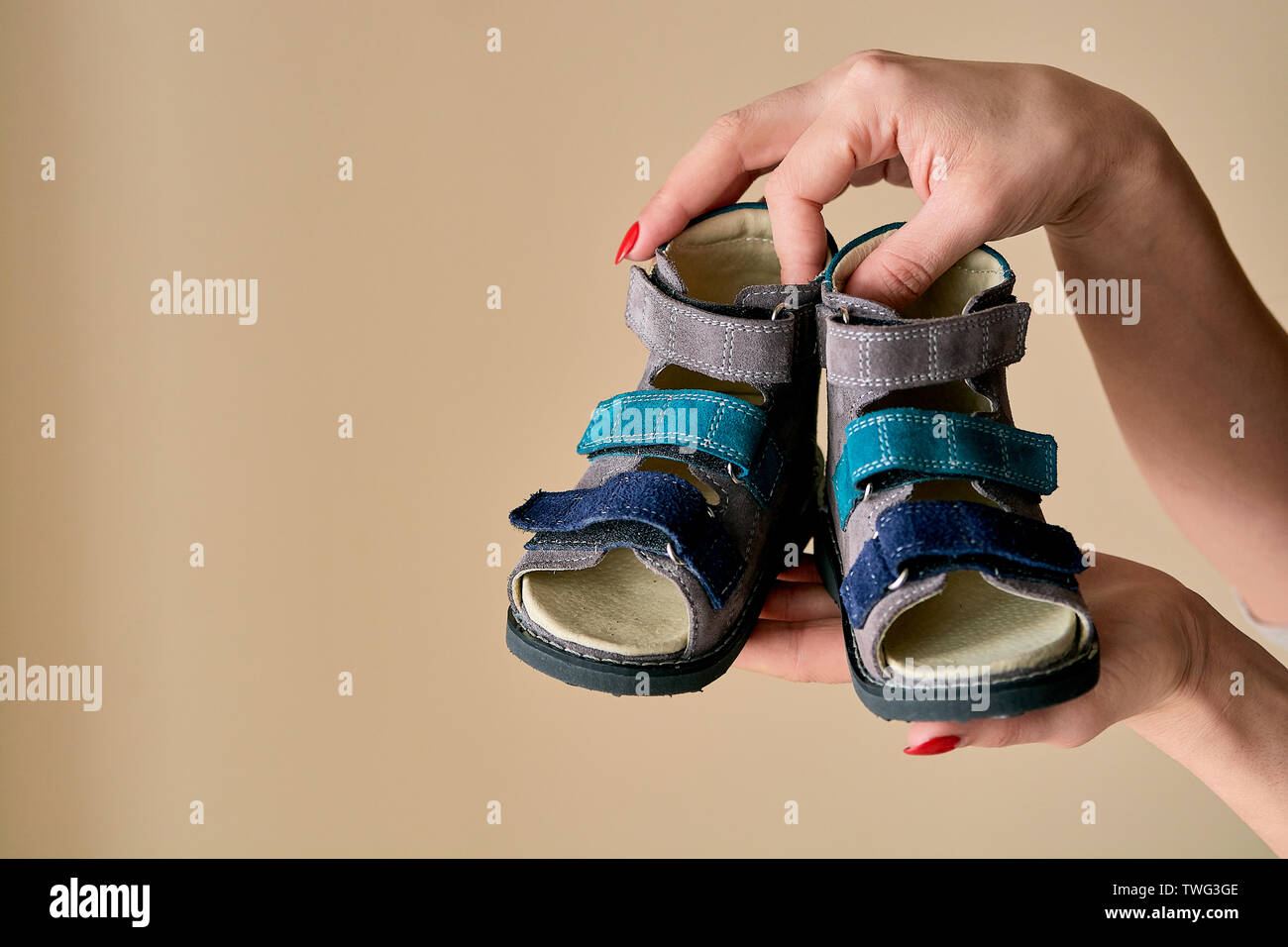 Weibliche hält Close-up ist ein spezielles Kinder orthopädische Schuhe Sandalen aus echtem Leder. Bequeme Schuhe auf hellen Hintergrund isoliert mit c Stockfoto