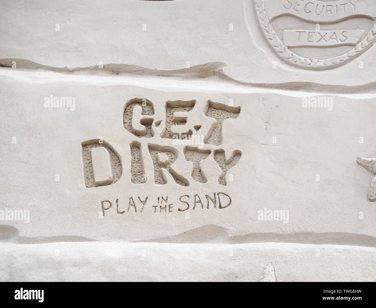 "Schmutzig Spielen im Sand", Slogan von Texas Sandfest2019 sculpted in Sand, Nahaufnahme. Port Aransas, Texas USA. Stockfoto