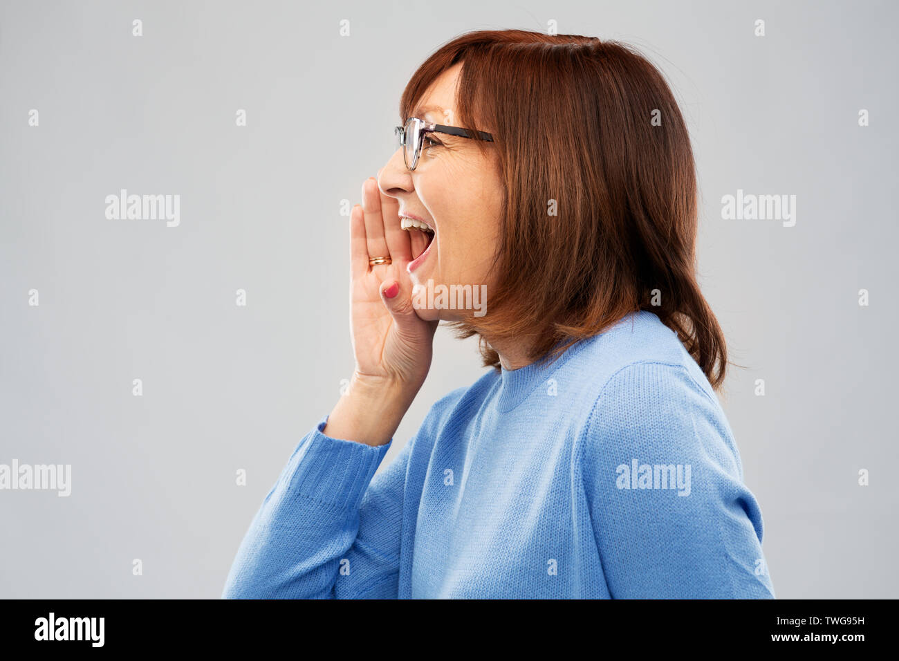 Ältere Frau in Gläser Aufruf über Grau Stockfoto