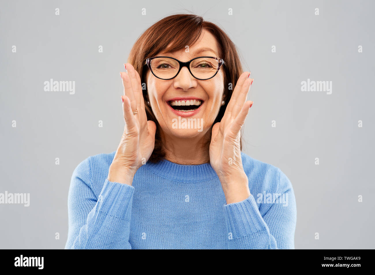 Ältere Frau in Gläser Aufruf über Grau Stockfoto