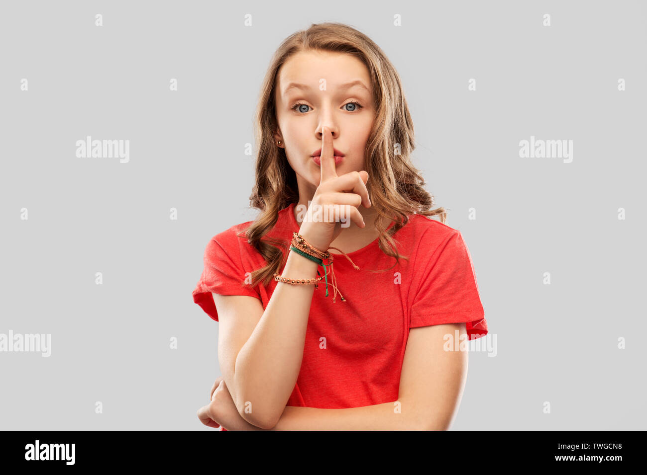 Teenage Mädchen im roten T-Shirt mit dem Finger auf den Lippen Stockfoto