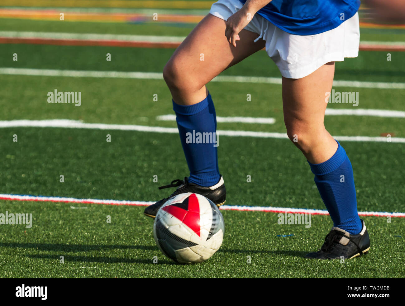 Ein Fußball-Spieler den Ball wie er unten läuft ein grüner Rasen Feld während eines Spiels. Stockfoto