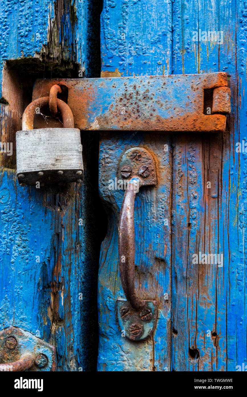 Vorhängeschloss und Verschluss mit Rost auf Risse und Peeling blaue Tür Stockfoto