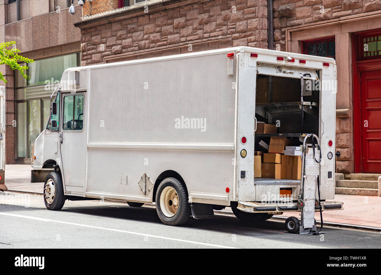 Von Tür zu Tür Lieferung. Pakete in eine weiße Farbe, Lkw mit offener Tür, auf einer Straße in der Innenstadt, New York geparkt Stockfoto