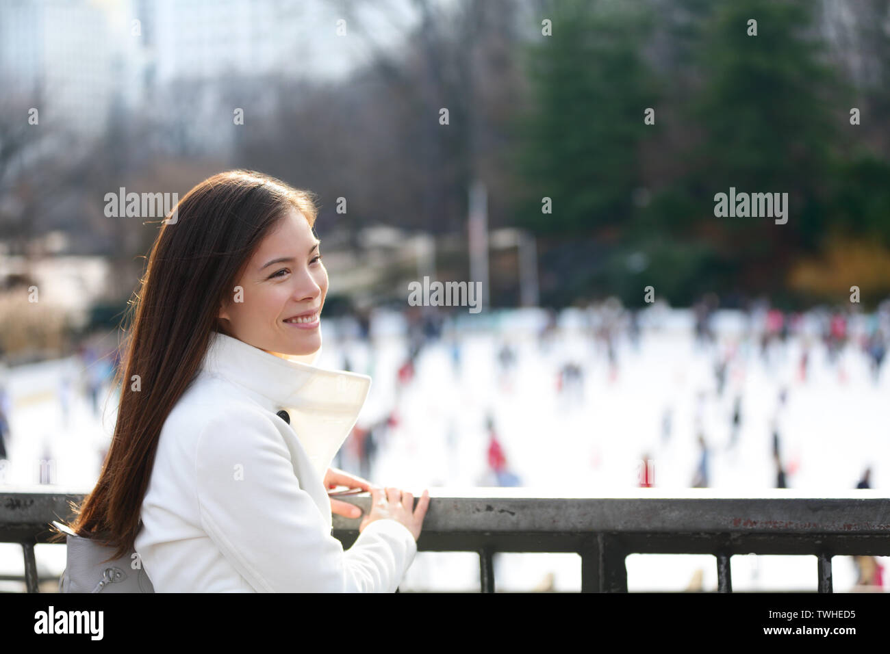 Frau im Central Park, New York City in den späten Herbst Winter mit Eisbahn im Hintergrund. Offenes Lächeln, multi-ethnischen Mädchen auf Manhattan, USA. Stockfoto