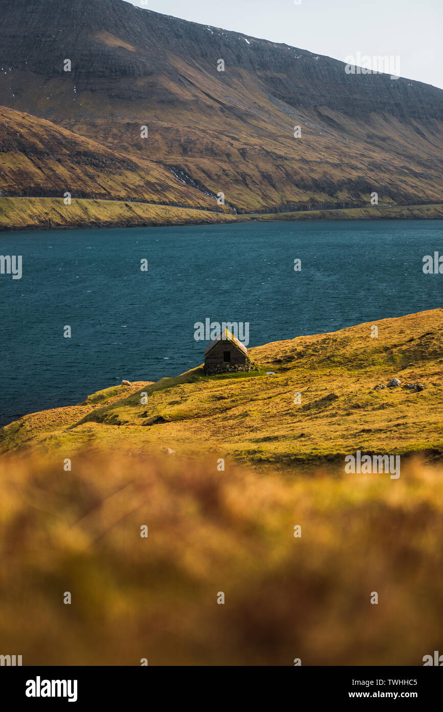 Kleine alte Fischer Hütte in den färöischen Fjord auf Wanderweg in Richtung Dranganir Cliff und Tindholmur Insel im Frühling Sonnenaufgang (Färöer Inseln) Stockfoto