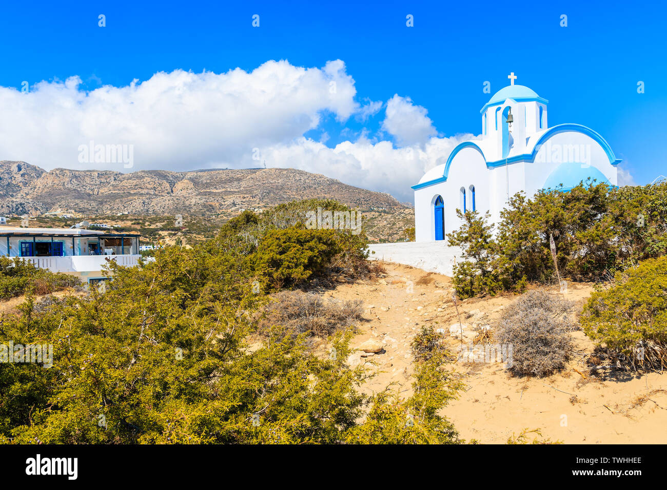 Weiße Kapelle mit Bergen im Hintergrund auf das Meer Küste in Ammopi Dorf, Karpathos, Griechenland Stockfoto