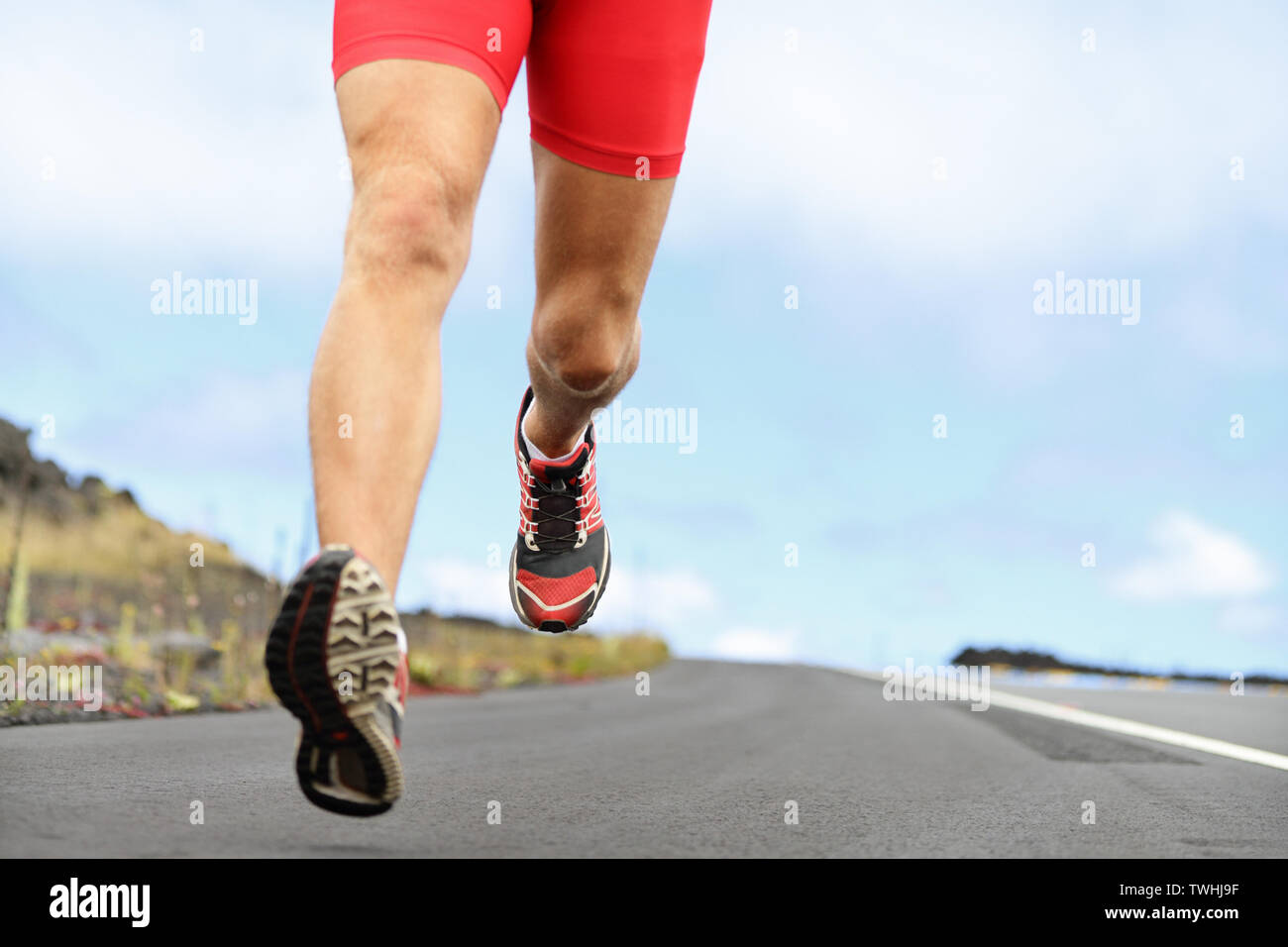 Laufsport Schuhe und Beine. Mann runner Beine und Schuhe in Aktion auf der Straße draußen bei Sonnenuntergang. Männliche Athlet Modell. Stockfoto