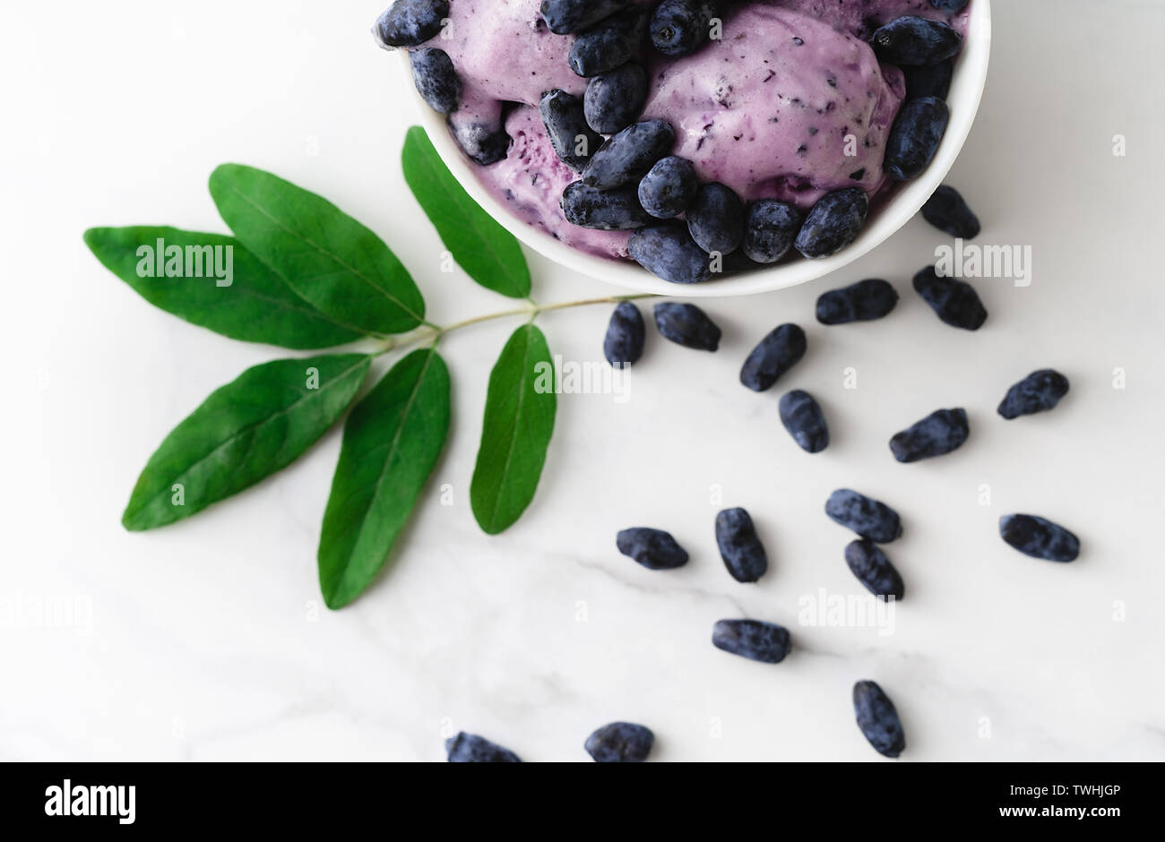 Eis mit frischen Beeren eines Geißblatt und grüne Blätter auf weißem Hintergrund eingerichtet. Ansicht von oben. Stockfoto