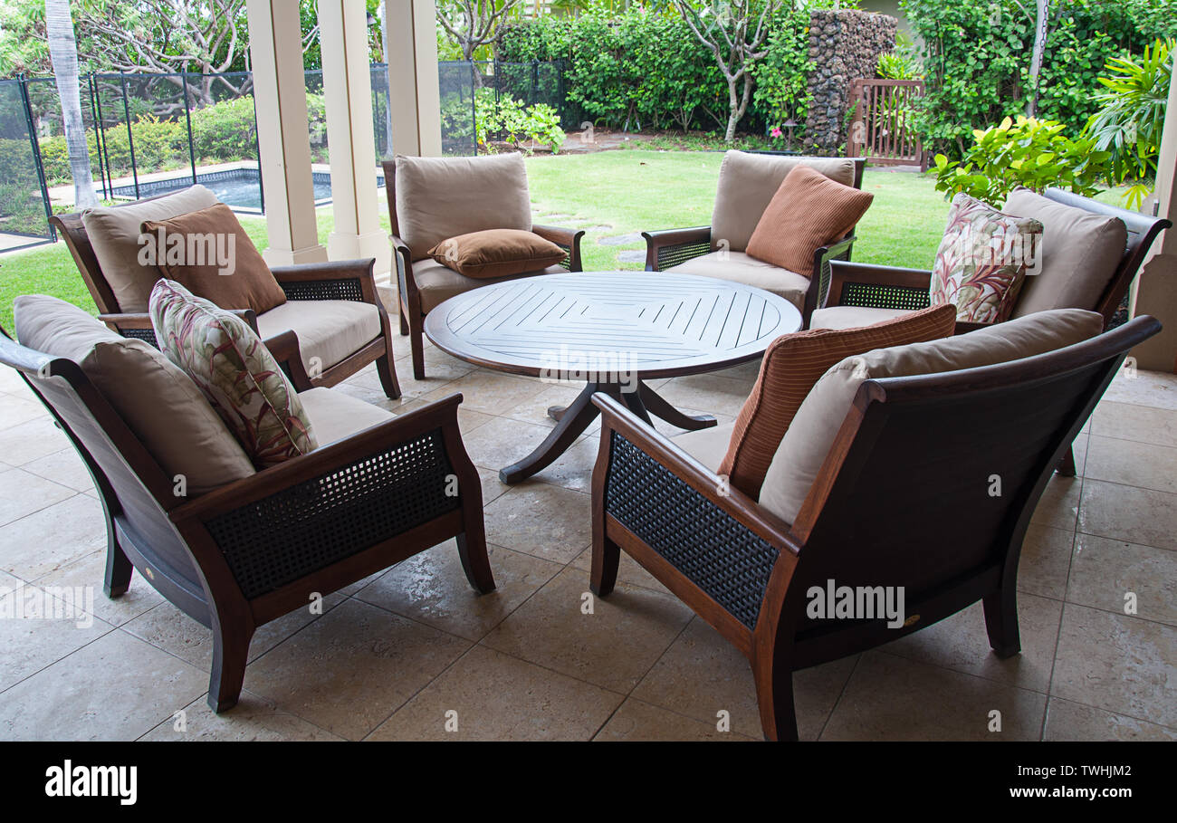Sitzecke auf tropischen Veranda mit einem runden Tisch und bequeme Stühle mit Kissen im Freien unter Abdeckung mit tropischen Hintergrund. Stockfoto