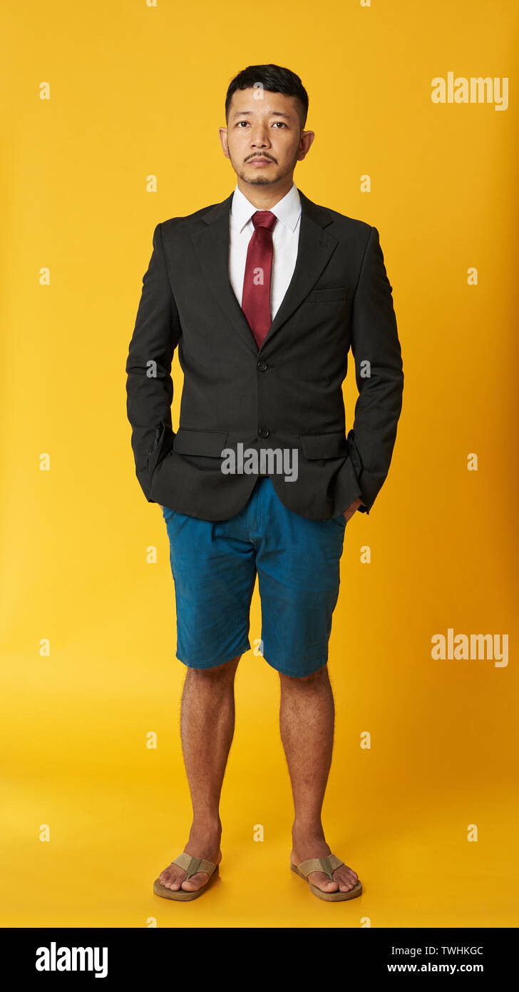 Asiatischer Mann in Anzug und Flip Flops auf gelbem Hintergrund Stockfoto