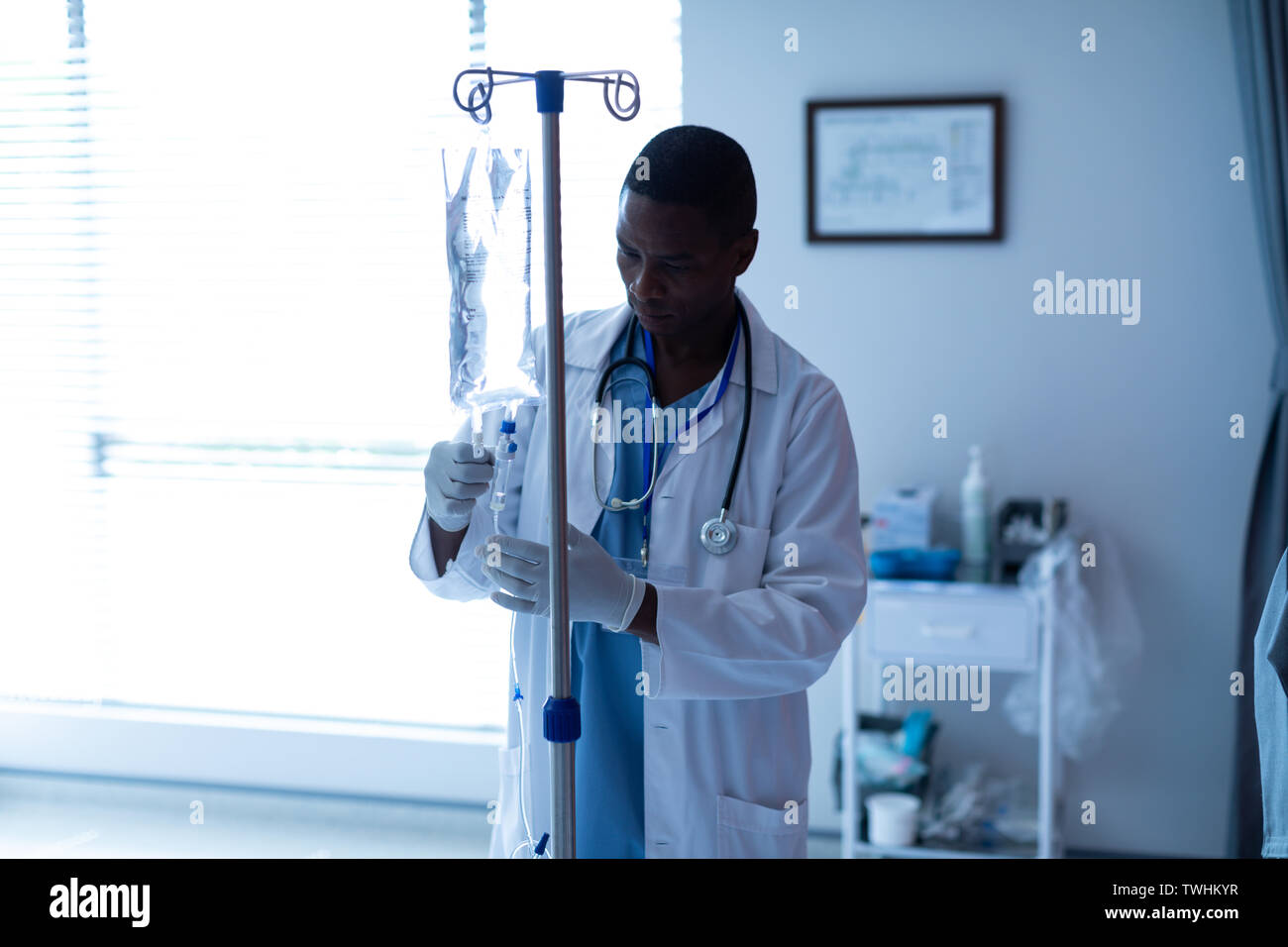 Männlicher Arzt prüfen intravenösen Therapie Tropfen in der Gemeinde Stockfoto