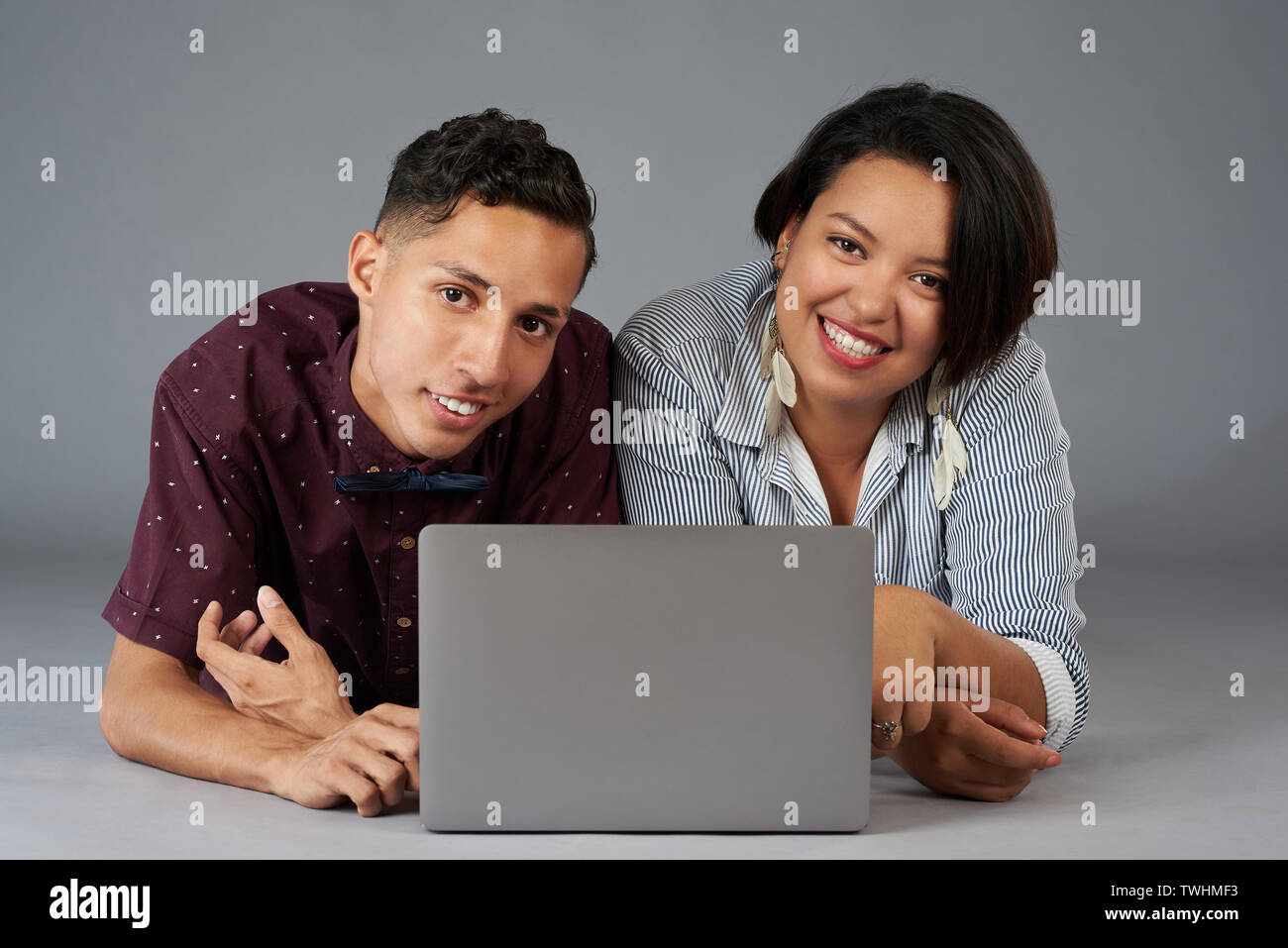 Junge hispanic Paar mit Laptop auf Grau studio Hintergrund isoliert Stockfoto