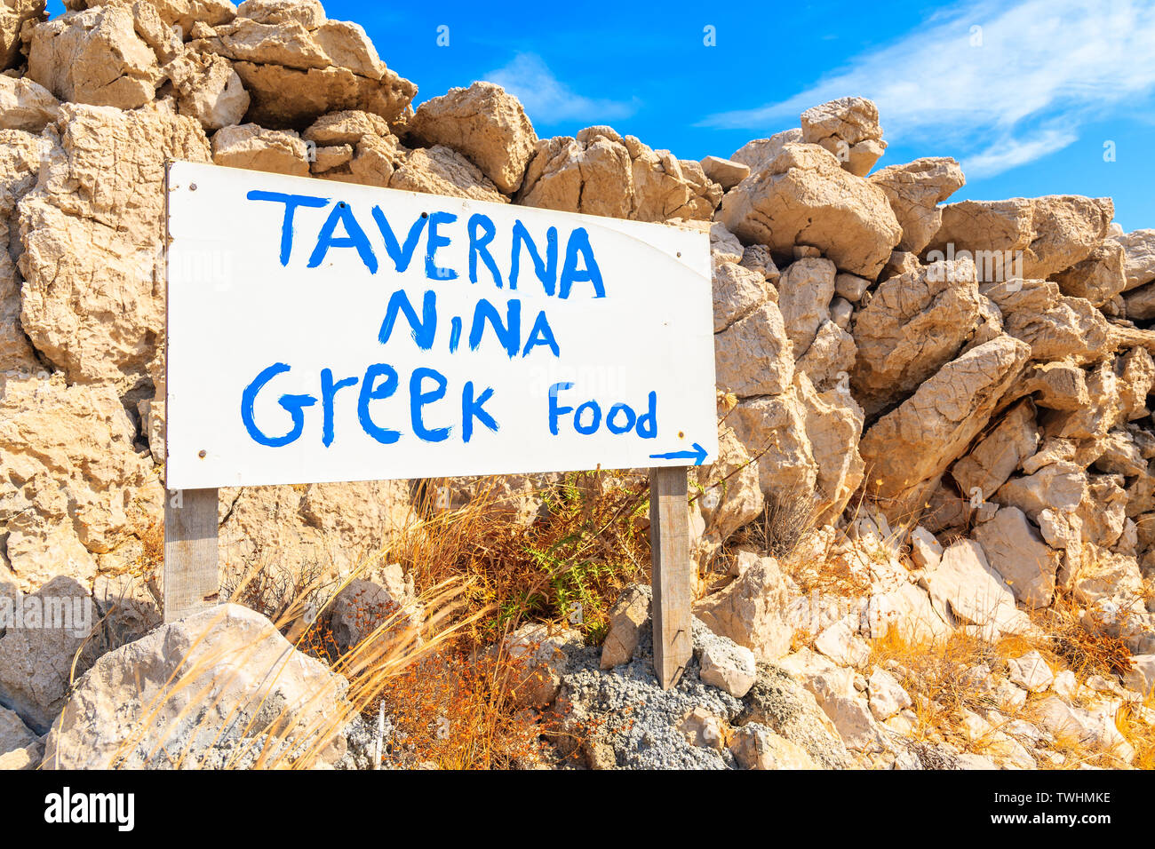 AMMOPI VILLAGE, Insel Karpathos - Sep 26, 2018: Weiße Zeichen der griechische Taverne vor Felsen auf Küstenweg in Ammopi Dorf. Griechische Inseln sind Fa Stockfoto