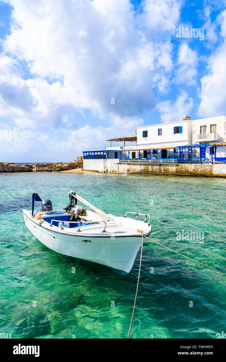 Weiß Fischerboot auf See im Ort Lefkos Port mit typischen Häuser am Ufer, Karpathos, Griechenland Stockfoto