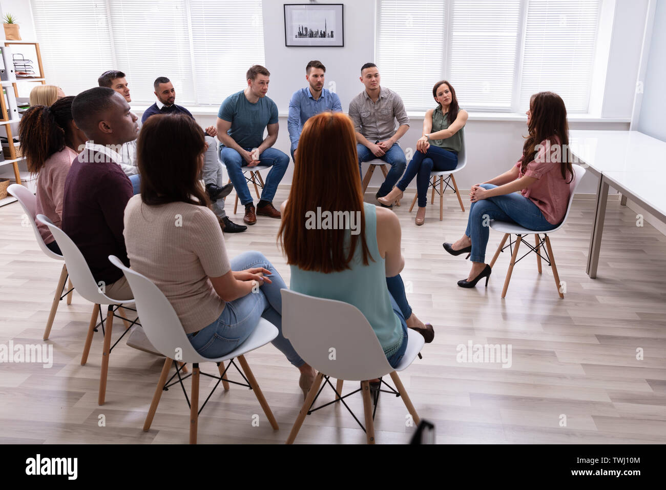 Junge weibliche Therapeuten, die Lektion zu multi-ethnischen Gruppe zu Therapie Abschnitt Stockfoto