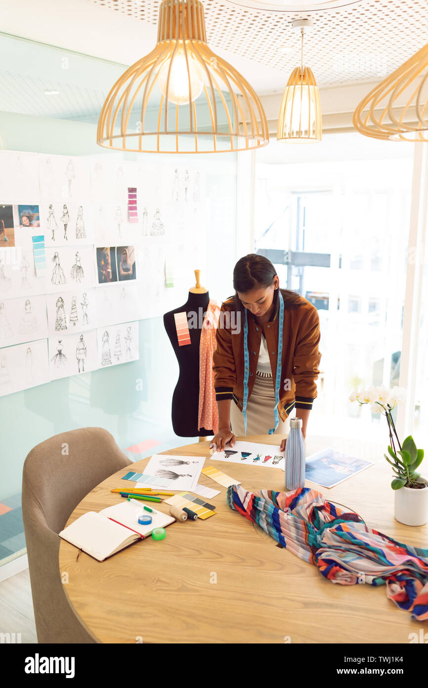 Weibliche Mode Designer bei Skizzen auf Tisch in einem modernen Büro Stockfoto