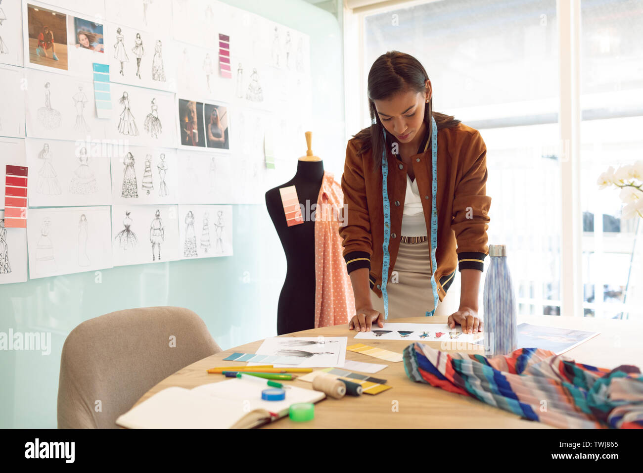 Weibliche Mode Designer bei Skizzen auf Tisch in einem modernen Büro Stockfoto