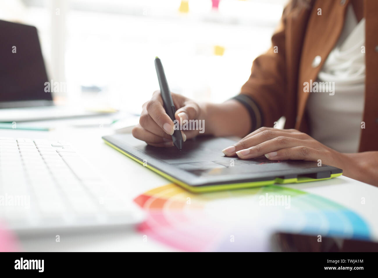 Weibliche Graphic Designer über Grafik Tablett am Schreibtisch in einem modernen Büro Stockfoto