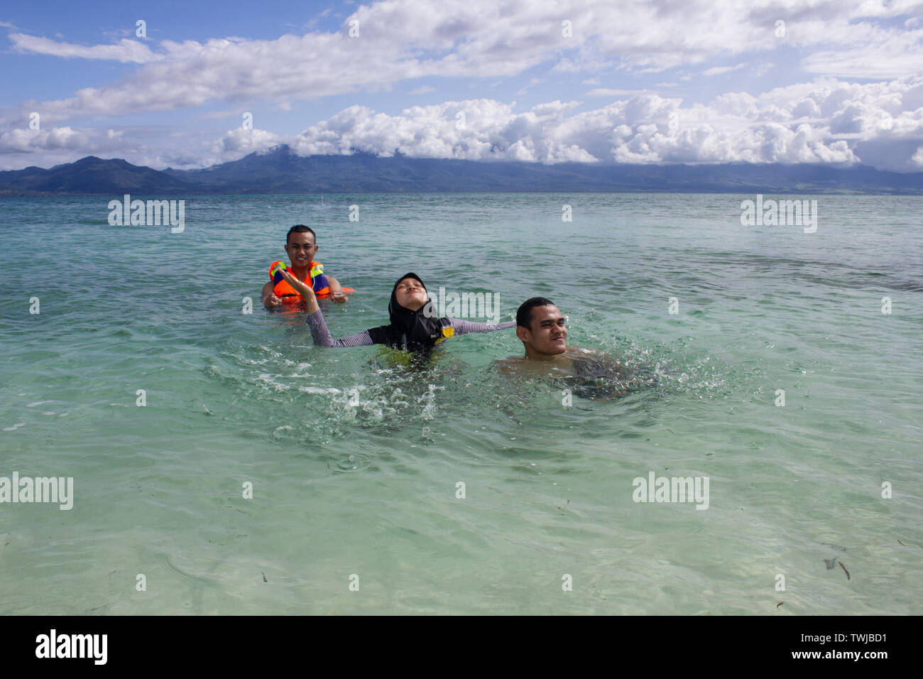 Drei muslimische Freunde genießen ihre Ferien durch Baden in klaren, weißen Sand im sonnigen Sommer Stockfoto