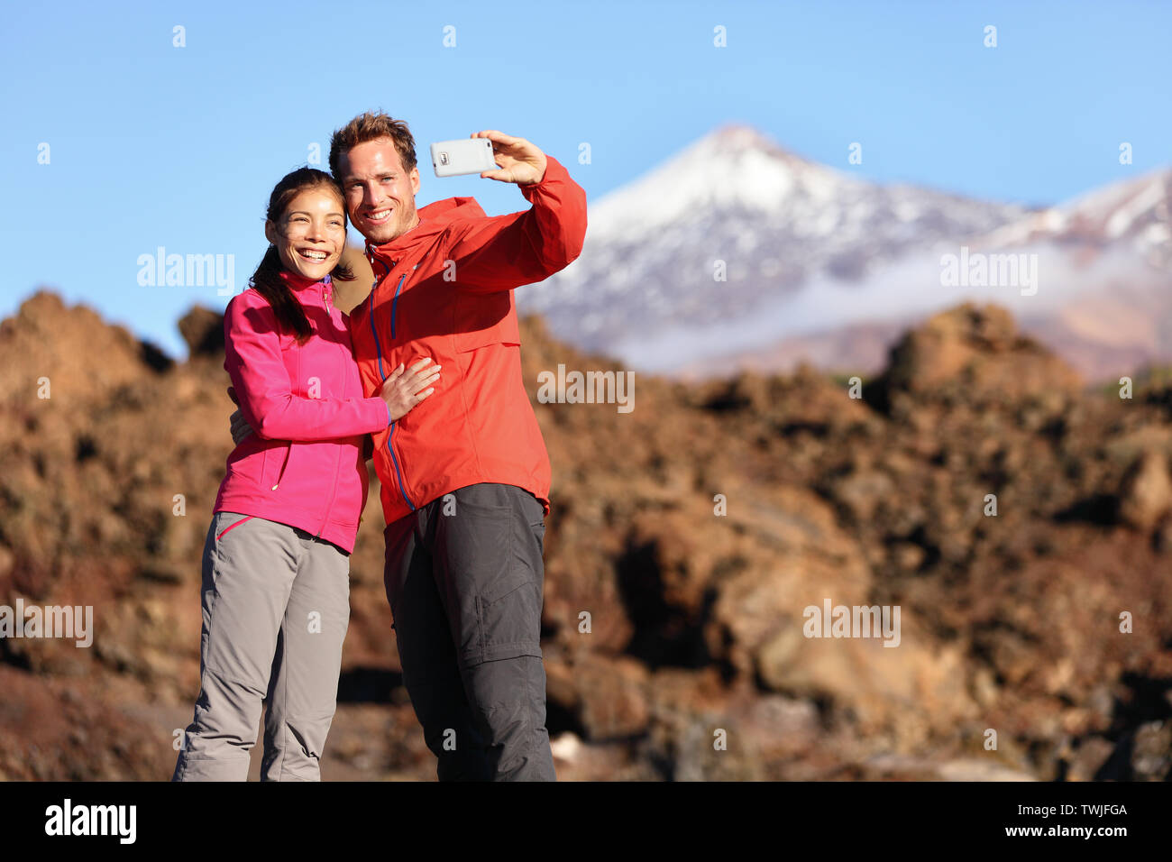 Paar unter selfie Wandern in schöner Natur mit Smart Phone. Glückliches Paar zu Fuß genießen Ansehen und Aufnehmen von Bildern mit Smartphone. Mann und Frau, die von Vulkan Teide auf Teneriffa, Kanarische Inseln. Stockfoto