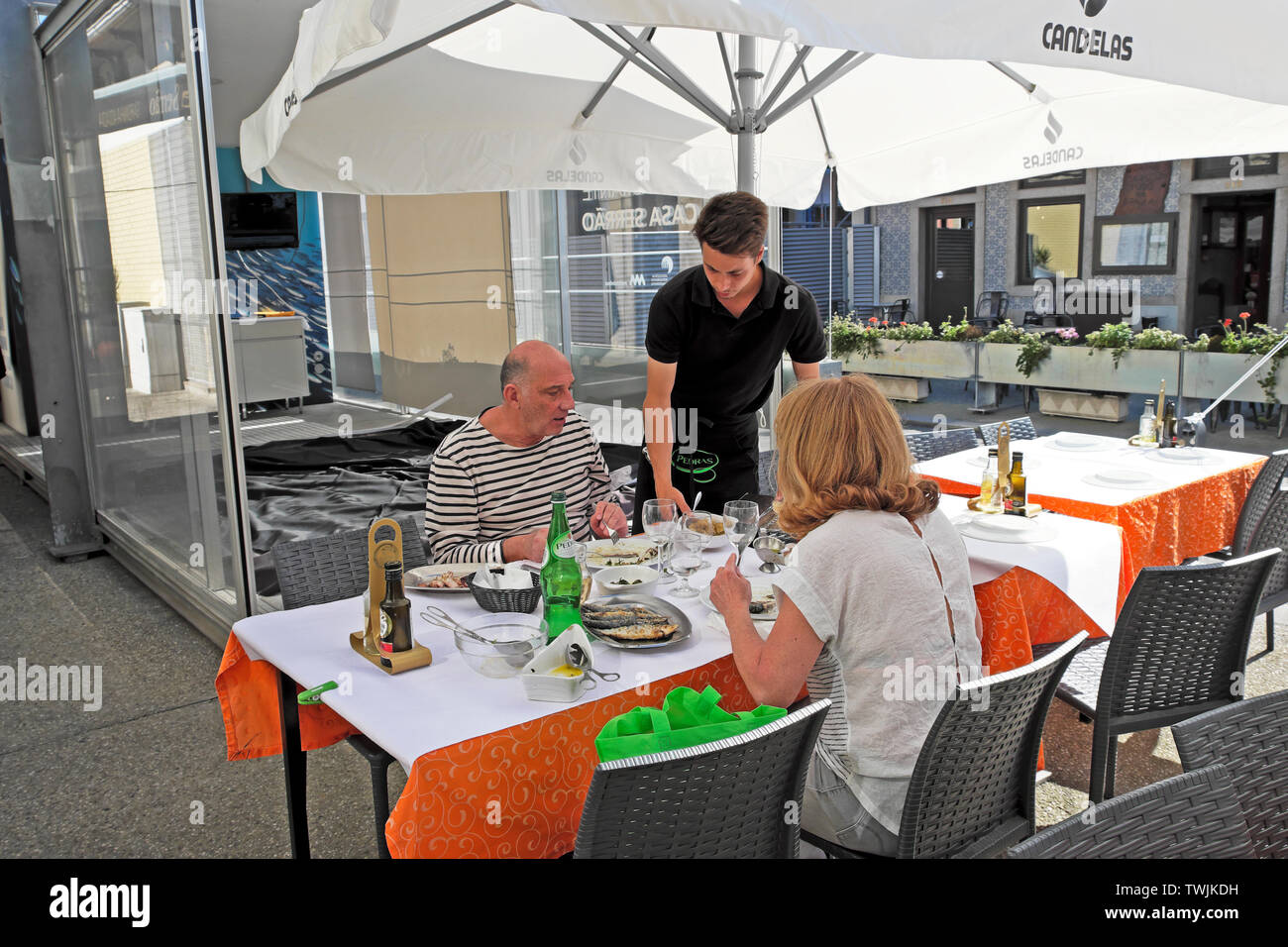 Junger Kellner älteres Paar im Freien Speisen servieren bei Seafood Restaurant sitzen essen Fisch essen am Tisch im Matosinhos Porto Portugal KATHY DEWITT Stockfoto