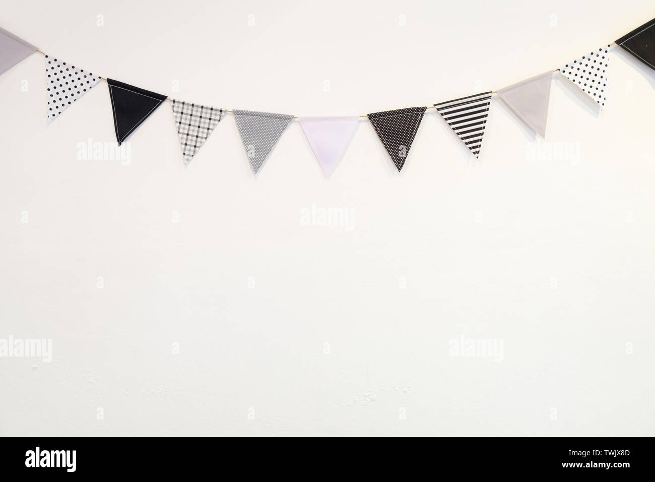 Kleine schwarze weiße Dreieck Form Flagge aufhängen Kurve nach unten Pflasterwand auf weißem Hintergrund Stockfoto
