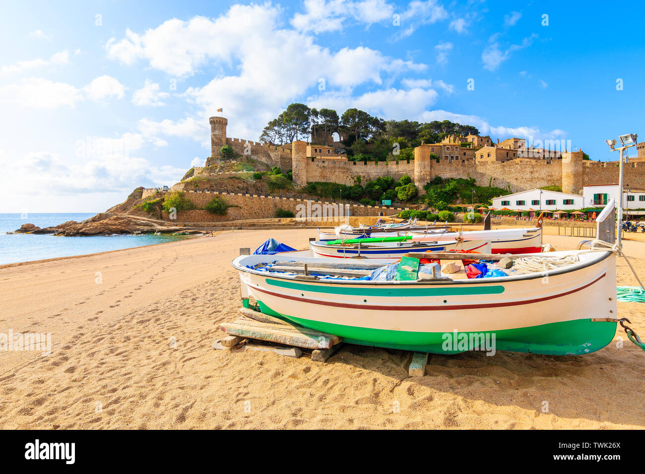 Fischerboote am goldenen Sandstrand in der Bucht mit Schloss im Hintergrund, Tossa de Mar, Costa Brava, Spanien Stockfoto