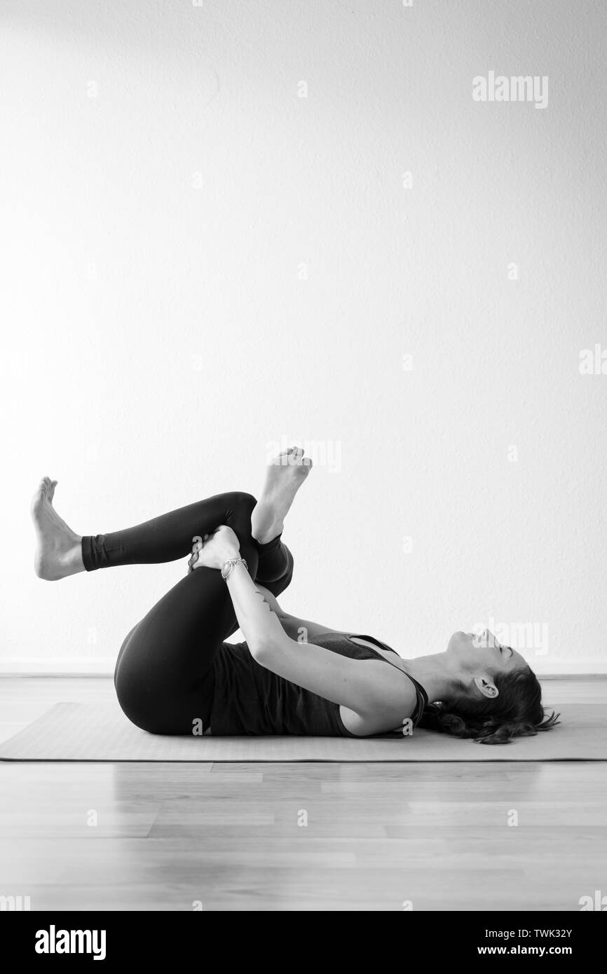 Junge europäische brünette Frau in liegender Taubenposition, auch als Rückentaube, tote Taube, Nadelauge oder Einfädeln der Nadel Yoga asana bezeichnet Stockfoto