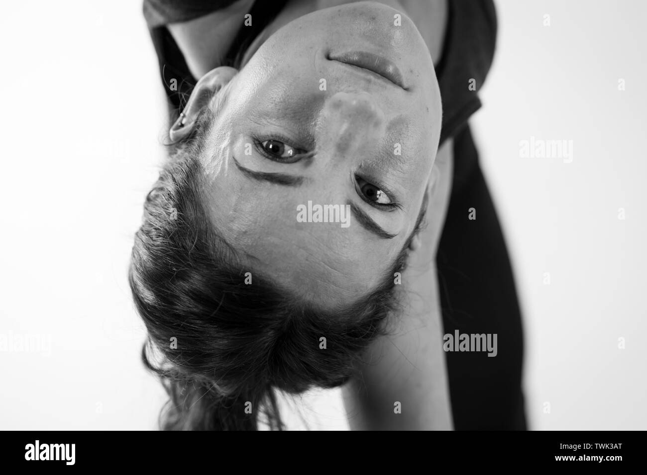 Eine dunkelhaarige Europäerin in ihren 30ern, die auf dem Kopf steht, während sie Asana- oder Yogapositionen beugt Stockfoto