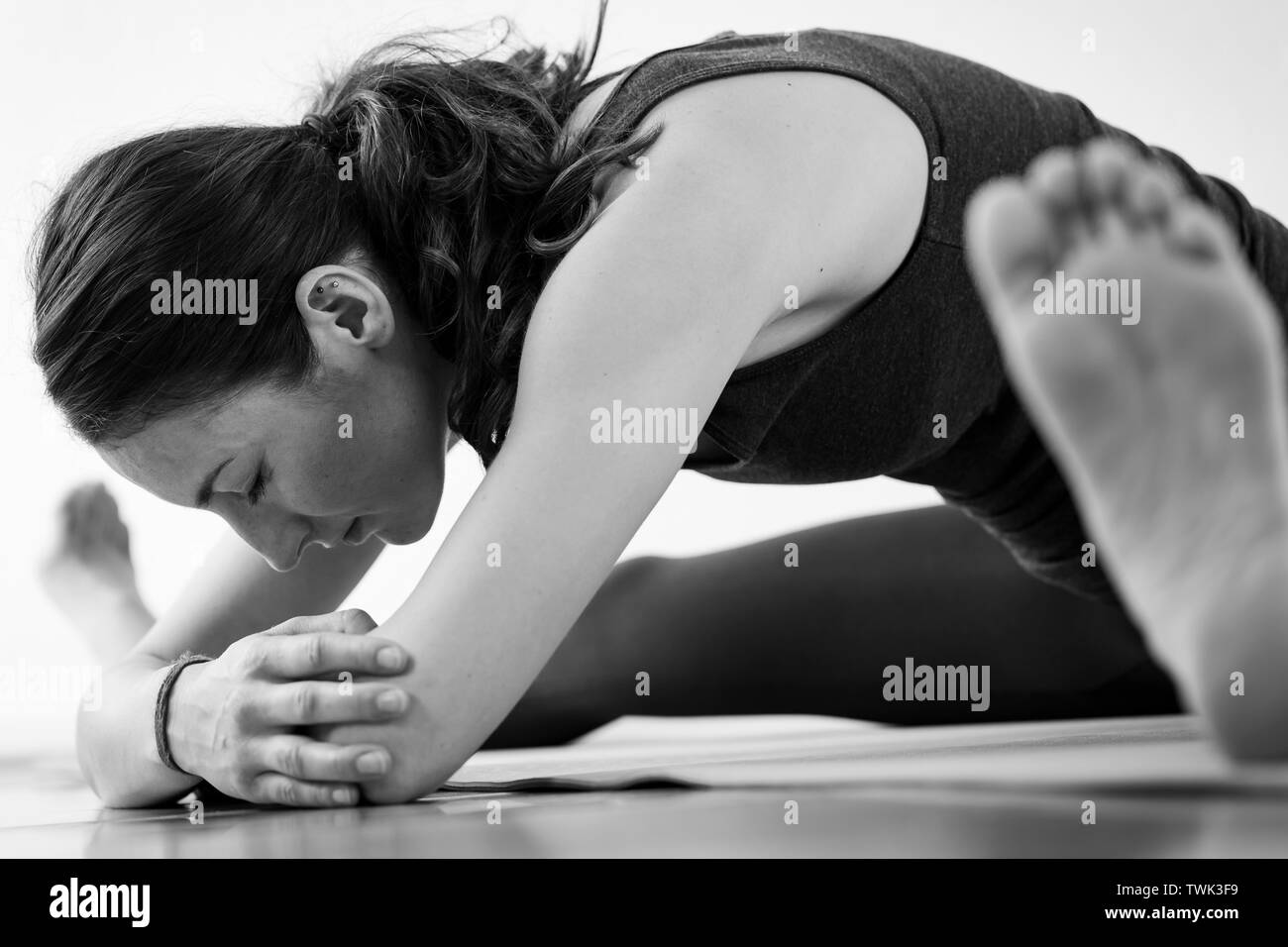 Close-up Seitenansicht eines brünette Frau in den 30er Jahren Yoga zu Hause, einen breiten Beinen nach vorne sitzt Asana biegen. Horizontales Format. Stockfoto