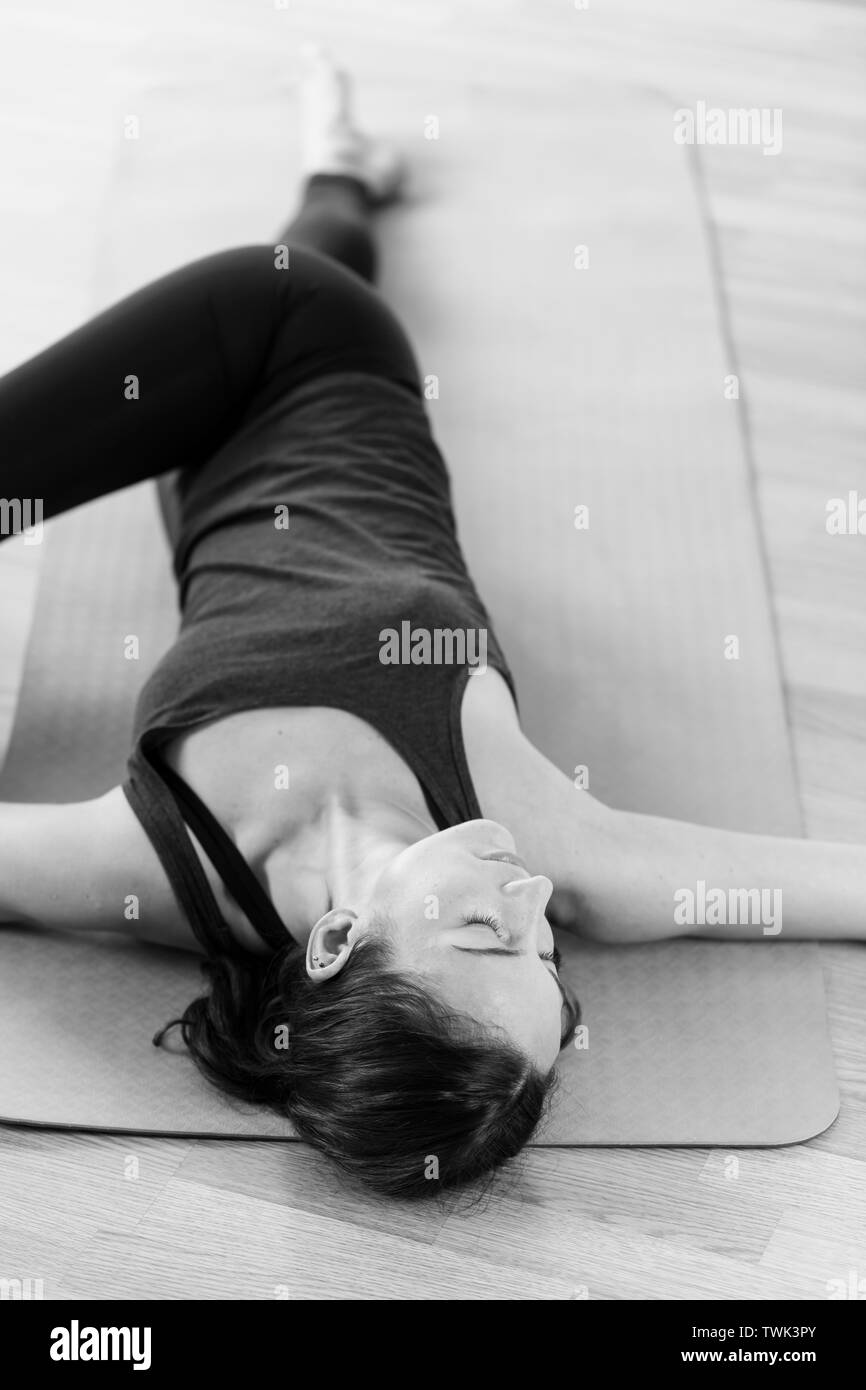 Eine Frau in den frühen 30er Jahren Yoga auf dem Boden, der die Wirbelsäule verdrehen Stellen in Ihrem Haus. Stockfoto