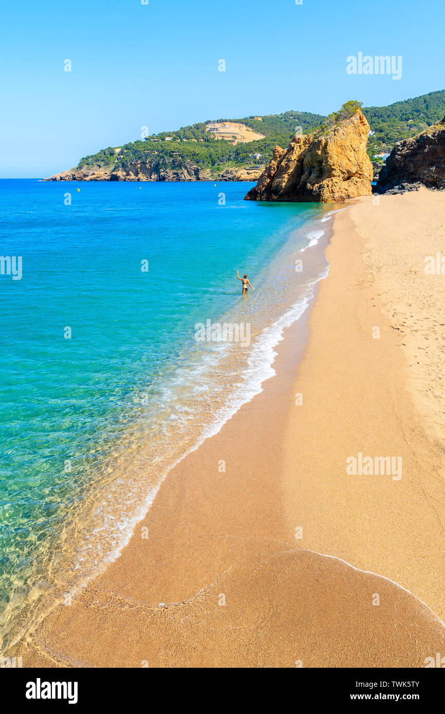 Nicht identifizierte junge Frau zu Fuß ins Meer Wasser an einem wunderschönen Strand in Cala Moreta, Costa Brava, Spanien Stockfoto