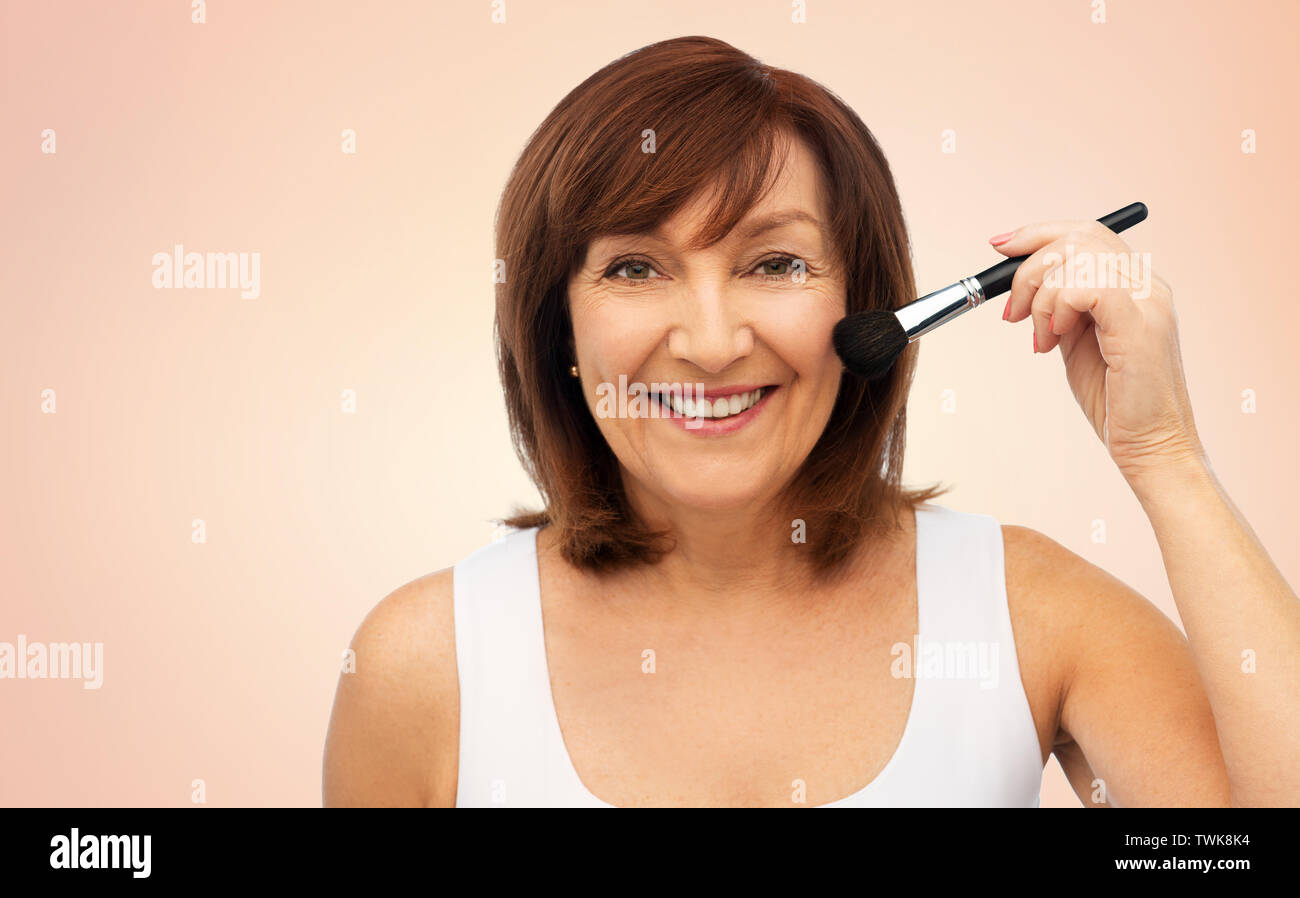 Lächelnde ältere Frau mit Make up Blush Pinsel Stockfoto