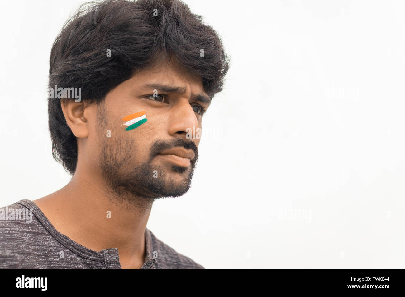 Portrait von neugierig oder angespannt Jungen Indischen männlichen Cricket Sport lackiert indische Flagge auf seinem Gesicht Stockfoto