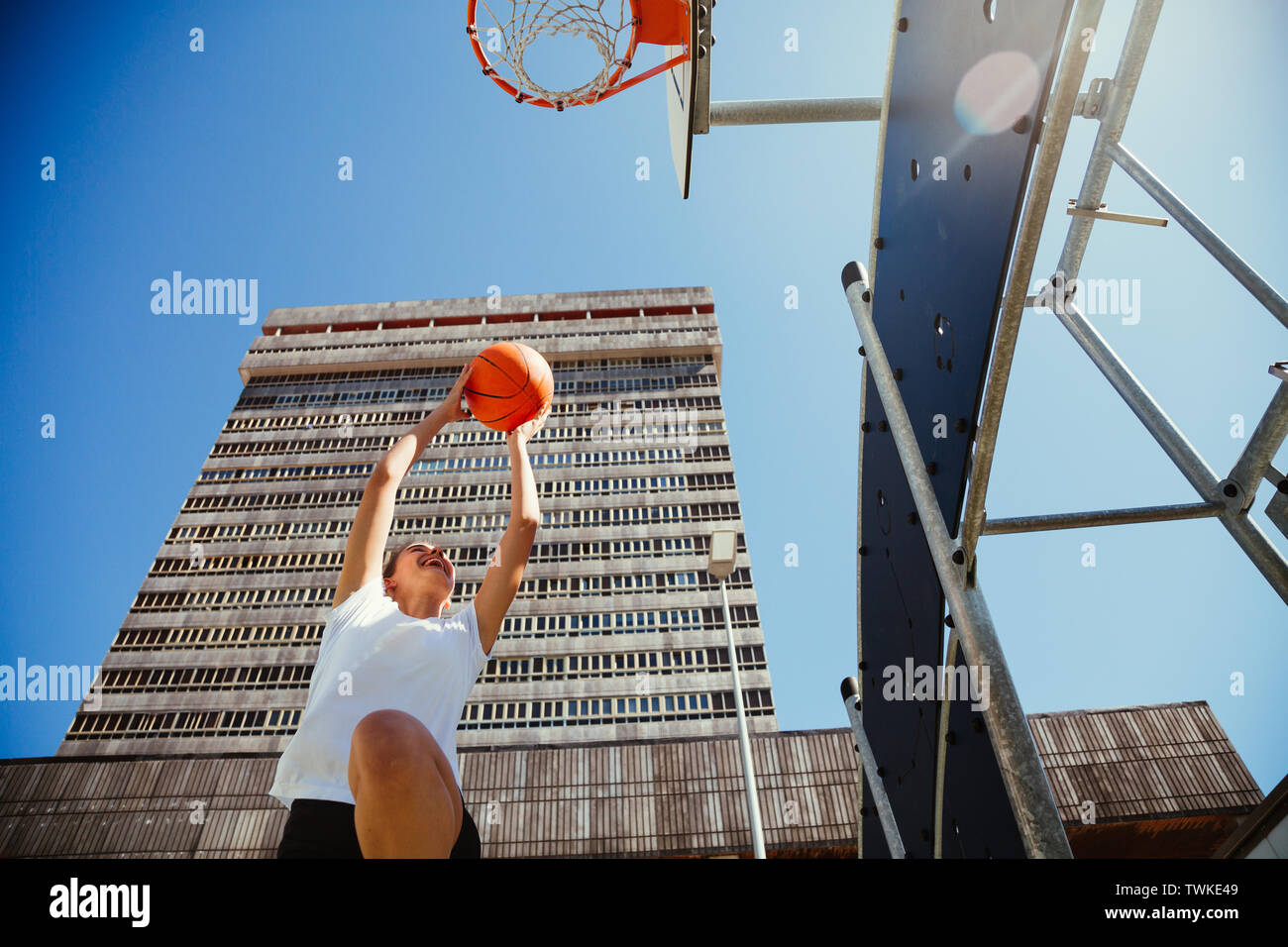 Junge weibliche Basketballspieler springen und werfen den Ball in den Korb in einem städtischen Gericht Stockfoto