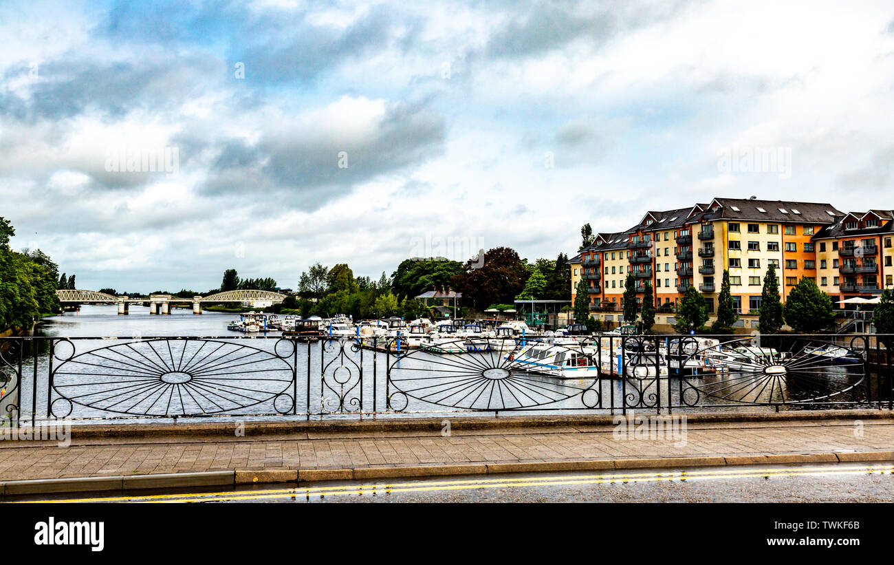 Blick auf den Fluss Shannon durch den Zaun der Schmied, Boote am Dock mit der S-Bahn Brücke im Hintergrund verankert Stockfoto