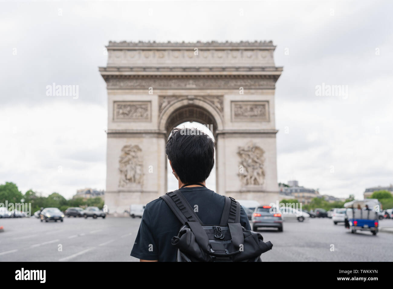 Ein Mann mit Rucksack, Arc de Triomphe, Wahrzeichen und Reiseziel in Paris, Frankreich. Unterwegs in Europa im Sommer Stockfoto