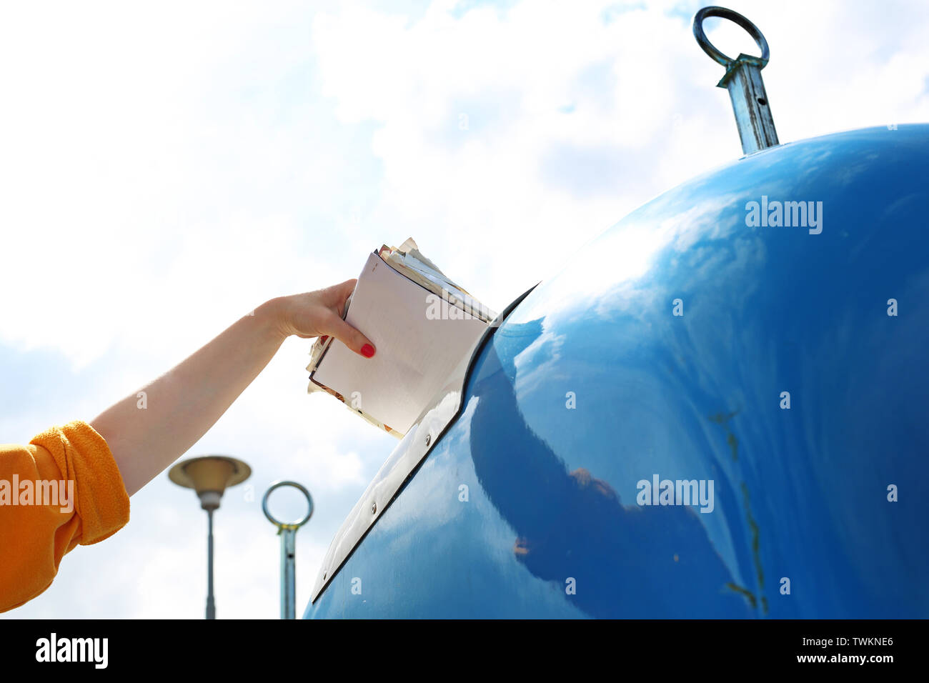 Recycling, eine Frau wirft Papier Abfall in einen blauen Container Stockfoto