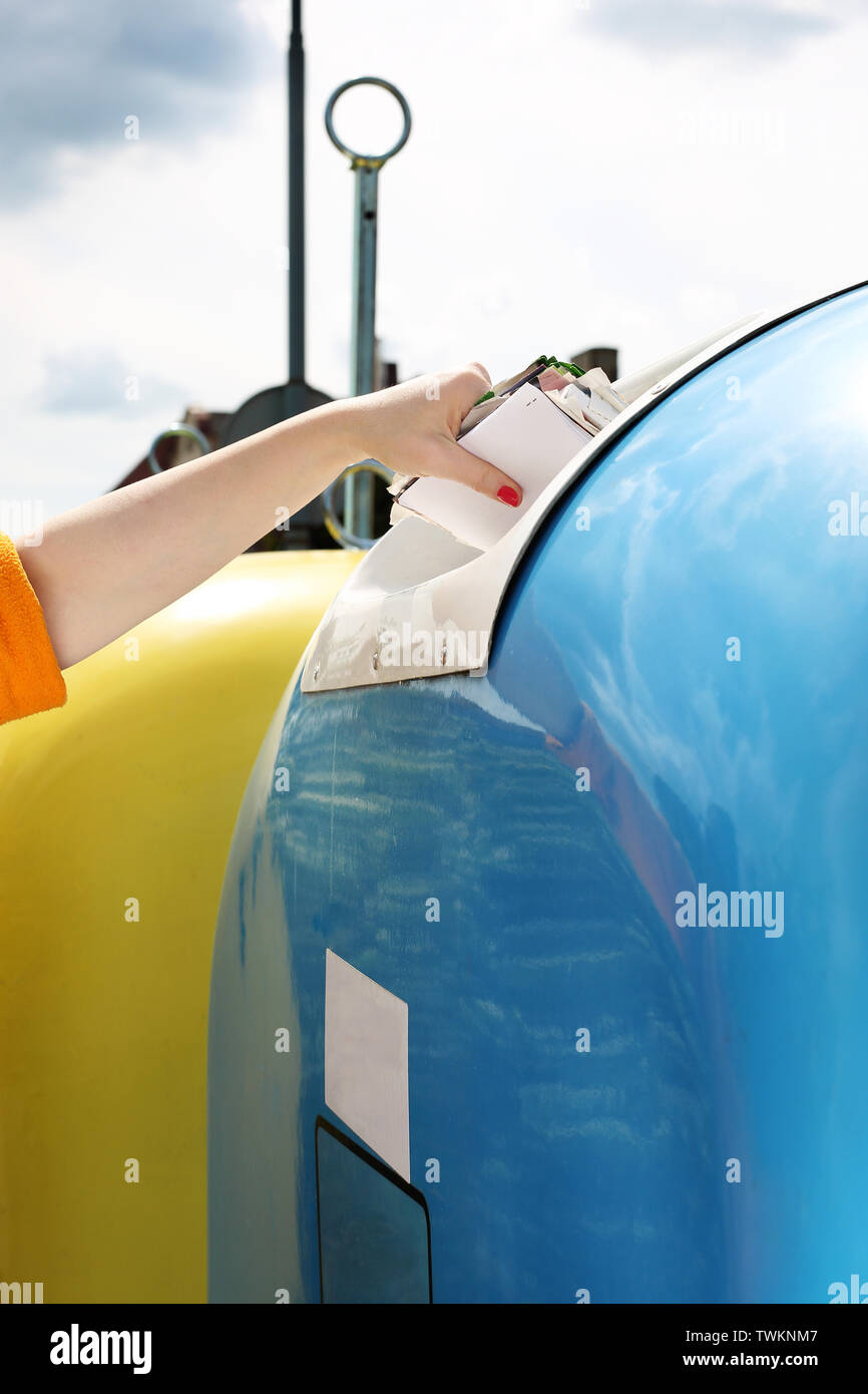 Recycling, eine Frau wirft Papier Abfall in einen blauen Container Stockfoto