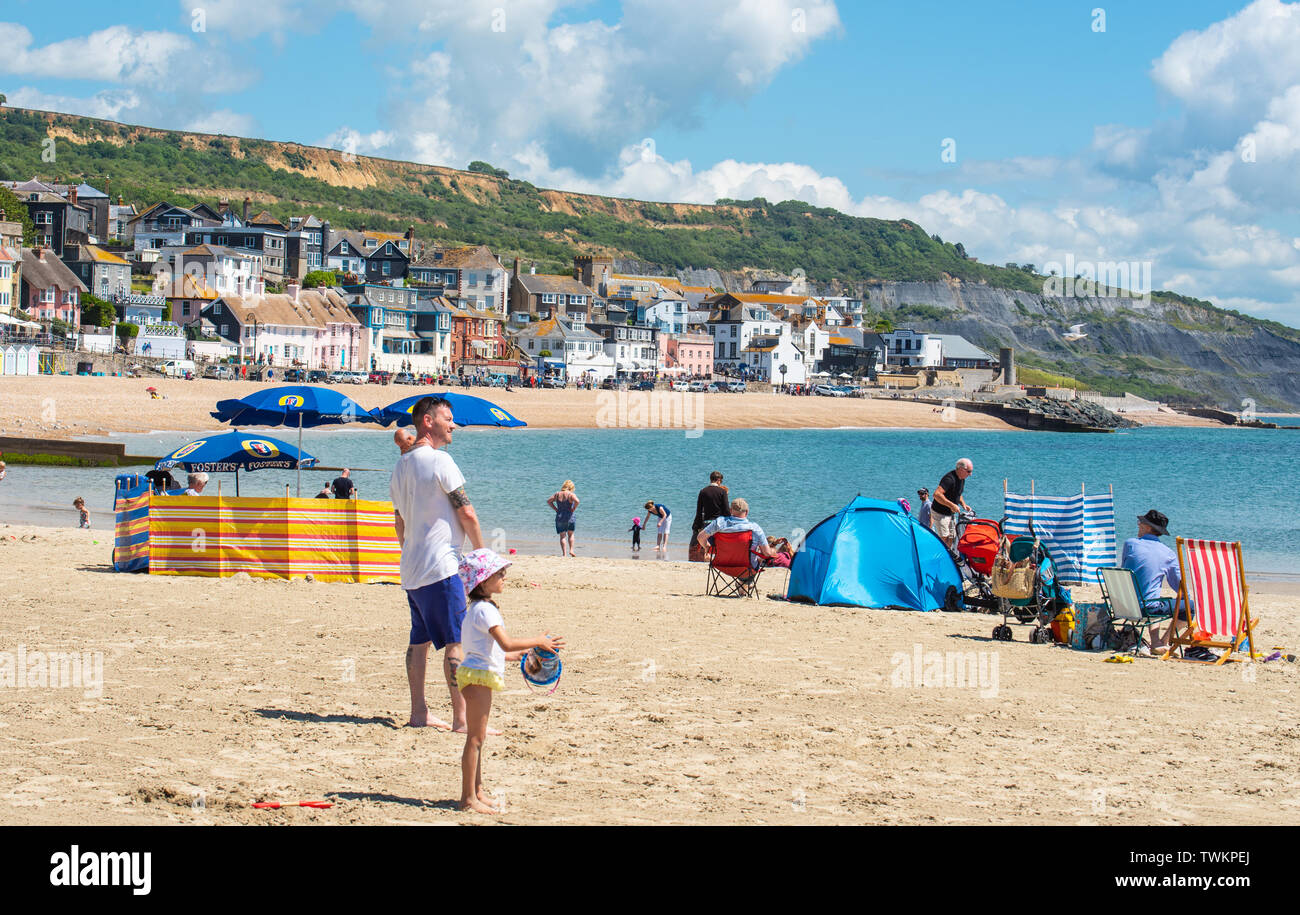 Lyme Regis, Dorset, Großbritannien. 21. Juni 2019. UK Wetter: Nach einem bewölkten Start in die Sommersonnenwende, herrlich warmen Sonnenschein zurück in den malerischen Badeort von Lyme Regis. Besucher genießen die willkommene Rückkehr der Sonne und blauen Himmel am Sandstrand und freuen Sie sich auf die warmen und sonnigen Bedingungen Prognose über das Wochenende. Credit: Celia McMahon/Alamy Leben Nachrichten. Stockfoto