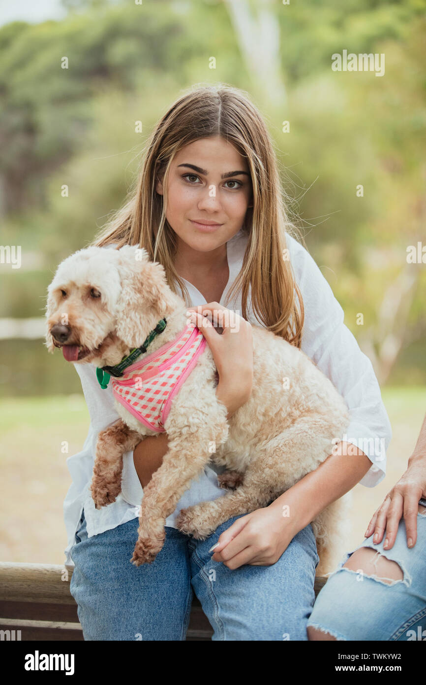 Ein junges Mädchen sitzt mit ihrem adorable Puppy auf ihrem Schoß im Freien. Stockfoto