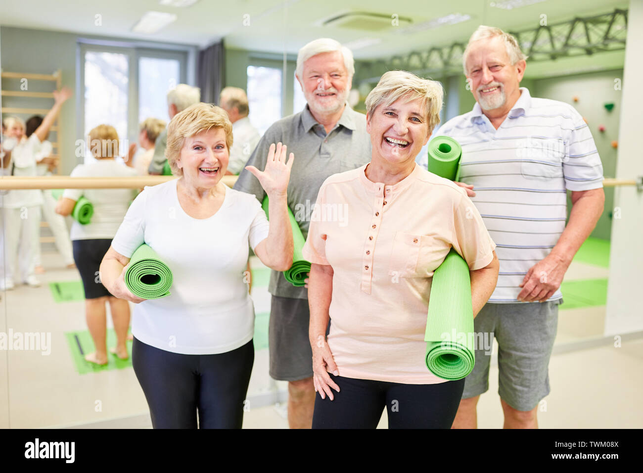 Glückliche Senioren mit Yoga Matten in der Turnhalle freuen sich auf die rückenübungen Stockfoto