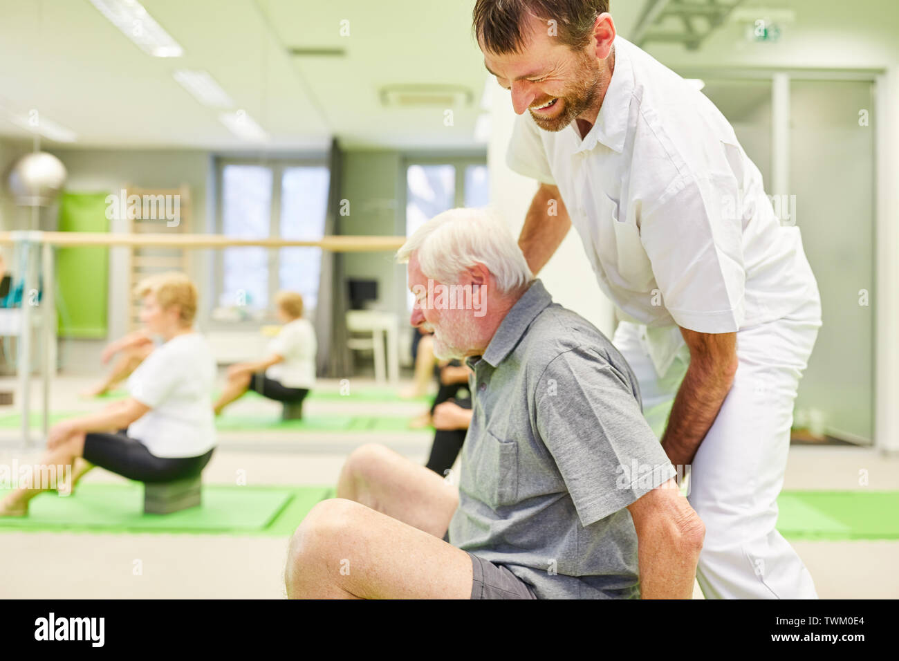 Physiotherapeutin gibt senior Hilfe bei einer Übung in der Schule in Reha Kurs Stockfoto