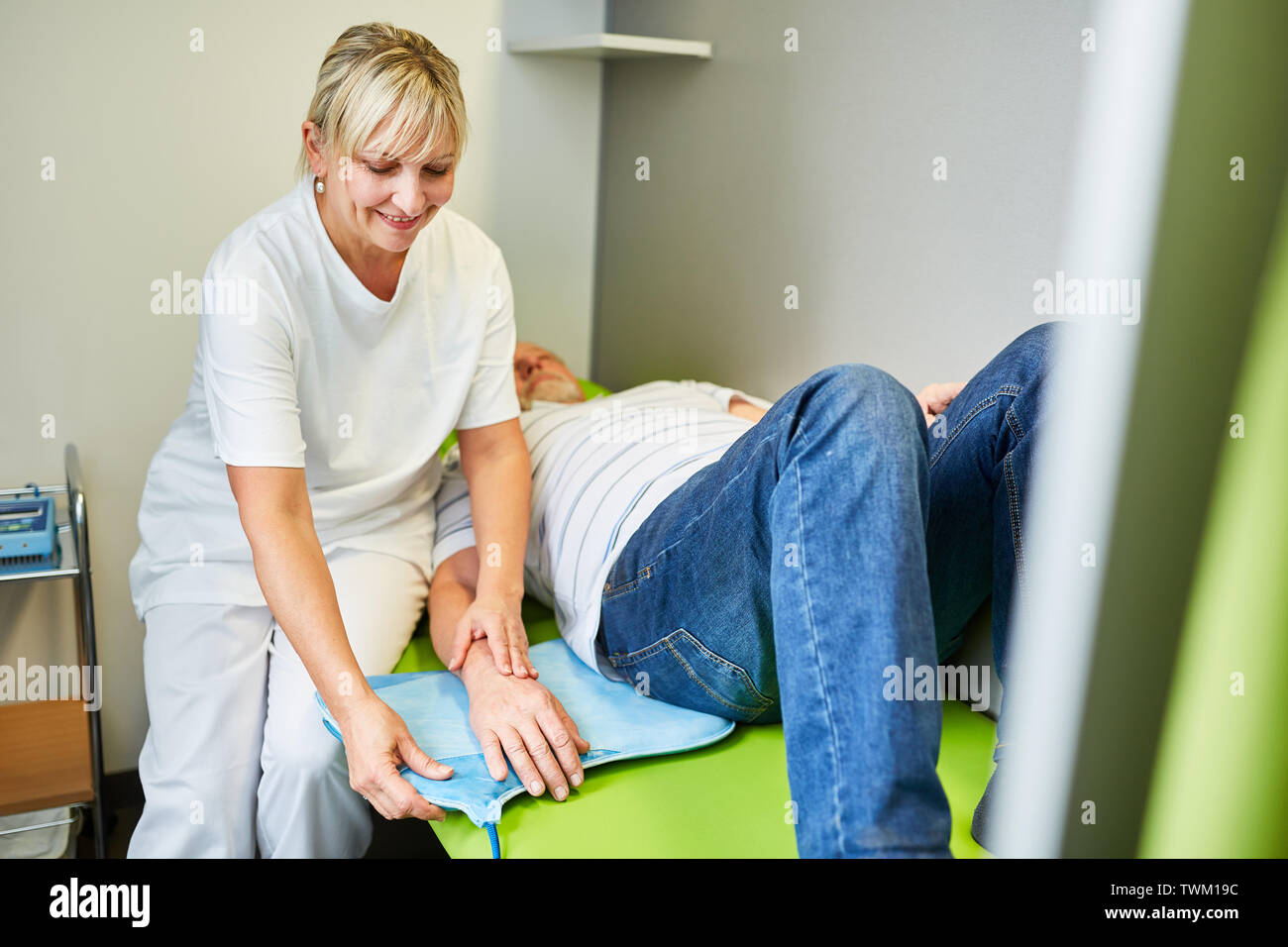 Heilpraktiker behandelt Patienten mit Rückenschmerzen in der Lendenwirbelsäule mit Magnetfeldtherapie Stockfoto