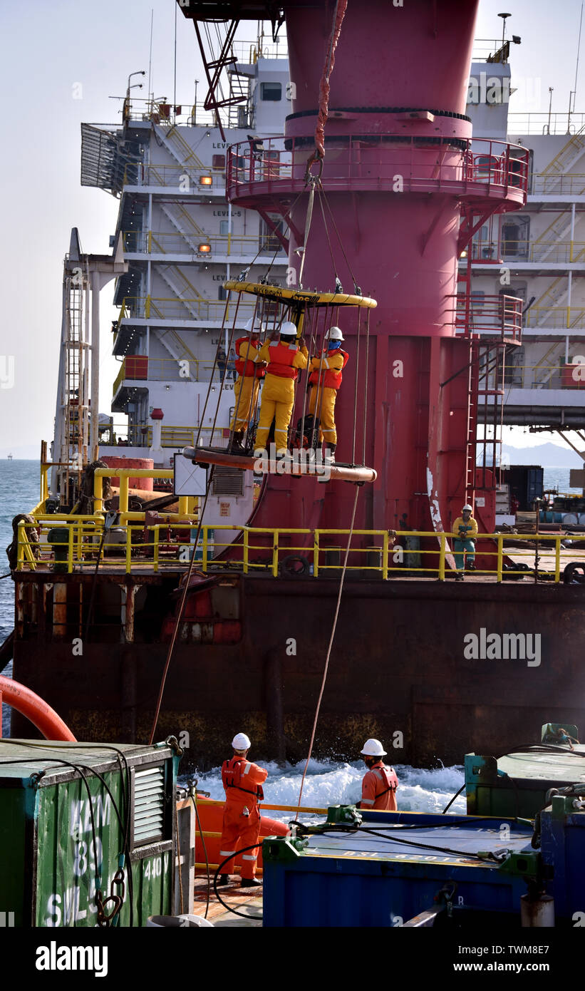 Marine Team übertragen von Öl Plattform Personal von der Unterkunft Barge zu Schiff mit dem Kran Stockfoto