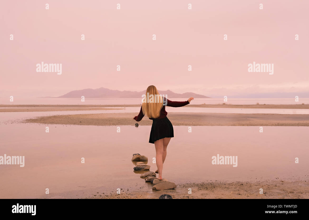 Blick auf die Rückseite einer jungen Frau mit langen blonden Haaren, wie Sie Flächen die große Szene der Great Salt Lake in der Ferne. Stockfoto